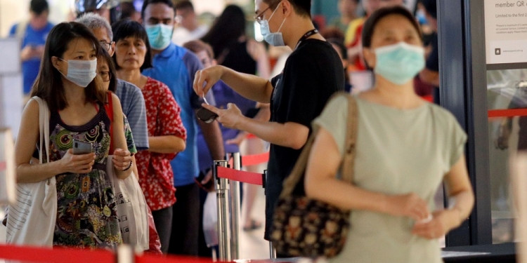 People queue to enter a mall, as mall capacity is regulated in a series of social distancing measures to curb the outbreak of coronavirus disease (COVID-19), in Singapore March 27, 2020. REUTERS/Edgar Su